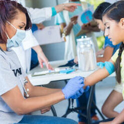 Volunteer doctor rubs alcohol on a young girl's arm while preparing to give the girl a flu shot.
